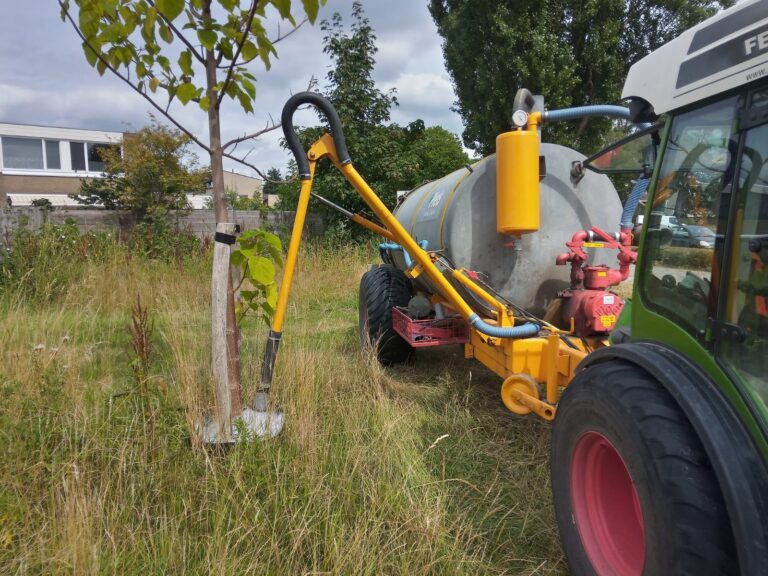 Bomen watergeven met tractor met waterton met sproeiarm