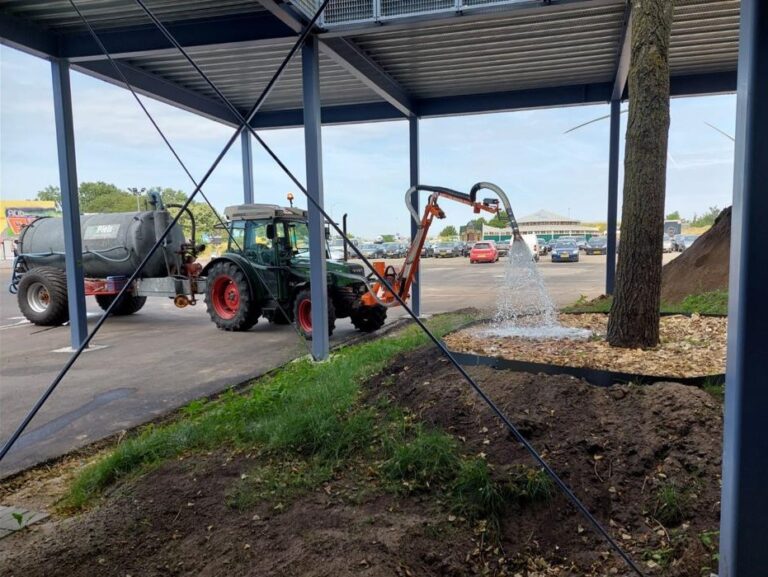 Bomen watergeven met tractor met waterton met sproeiarm